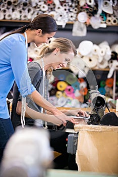 Sewing, machine and training woman in workshop, learning to work with fabric and process in fashion. Tailor, mentoring