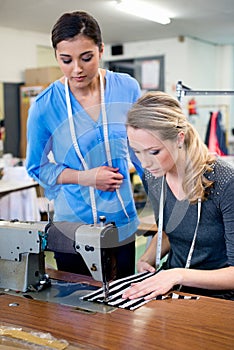 Sewing, machine and woman in training workshop, learning to work with fabric and process in fashion. Tailor, mentoring