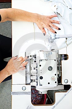 Sewing on a machine. Working woman sews on the sewing room sewing machine.