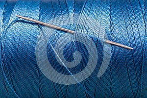Sewing needle in blue thread bobbin