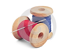 Sewing needle and colorful sewing thread on wooden spool on isolated white background