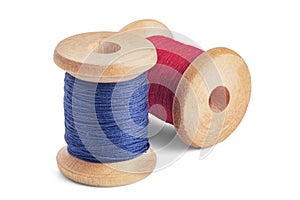 Sewing needle and colorful sewing thread on wooden spool on isolated white background