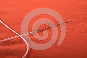 Sewing needle with white thread attached to it