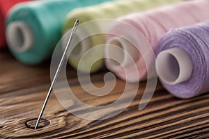Sewing needle on a wooden background in thread