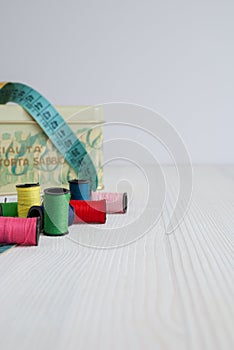 Sewing objects, threads, tape measure and tin box.