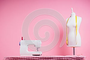 Sewing pattern,sewing machine and maniken in studio pink background.seamstress curve template. tailor creates a