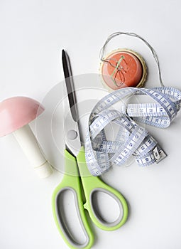 Sewing scissors, measuring tape and thread with a needle. Sewing kit