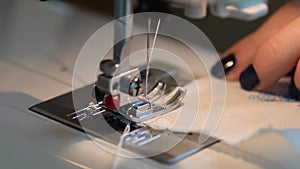 Sewing on a sewing machine. Close up of a carriage and a needle and thread making the first stitches on the fabric