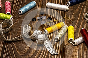 a sewing still life with a plastic ruler, needles, colored buttons, tape measure, assorted threads, golden vintage scissors on a