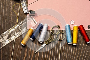 a sewing still life with plastic ruler, tape measure, assorted threads, golden vintage scissors on brown wooden table