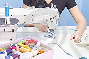 sewing Studio. seamstress sewing on a sewing machine close-up. A set of items for needlework: threads, needles, pins, scissors, ta