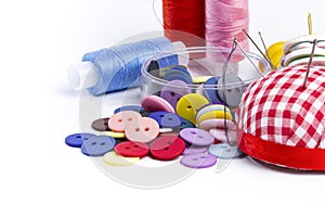 Sewing supplies, needles, thread and buttons on white, home craft or hobby concept