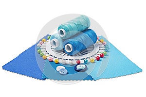 Sewing  thread, needle, bobbins, buttons and fabric samples in blue, light blue color on isolated white  background