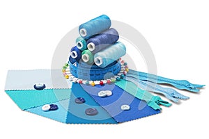 Sewing  thread, needle, bobbins, buttons, zipper  and  fabric samples  blue  color on isolated white  background