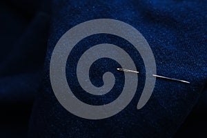 Sewing thread and needle at jeans denim background texture. Tailor handmade jeans denim concept