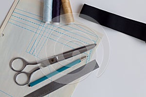 Sewing thread, pencils, ruler, scissors and patterns on a white table of a fashion designer