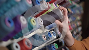 Sewing thread on a spool.Colorful spools of thread at a textile factory. Multi-colored thread. female hand puts several