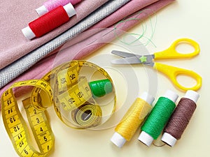 Sewing thread spools, measuring tape, colorful textile and scissors. Sewing supplies, and accessories for needlework, stitching