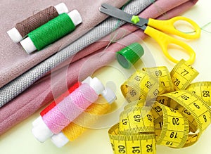 Sewing thread spools, measuring tape, colorful textile and scissors. Sewing supplies, and accessories for needlework, stitching