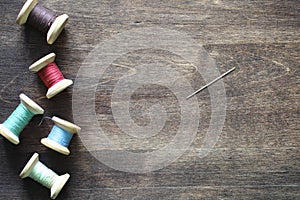 Sewing thread on a wooden background. Set of threads on bobbins retro style. Vintage accessories for sewing on the table