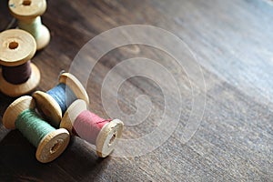 Sewing thread on a wooden background. Set of threads on bobbins