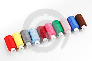 Sewing threads of different colors on reels on a white background. Free space, close-up. Isolate