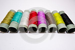 Sewing threads of different colors on white background.