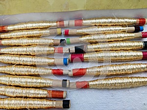 Sewing threads golden color closeup, gold silk spindle in paper basket using handloom