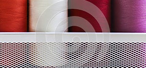 Sewing threads on spool in the white metal grid box.