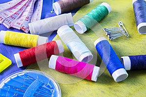 Sewing tools with colorful threads above silk fabric