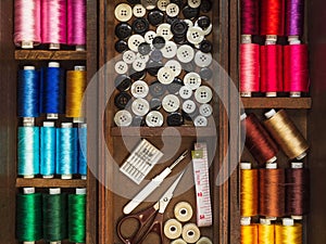 Sewing tools and multi colorful threads in wooden box, flat lay picture