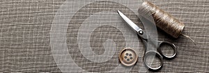 Sewing Tools: Scissors, Thread Spool, and Button on Rustic Fabric Texture