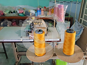 Sewing workshop with golden threads, sewing machines and spools of thread of different colors. Clothing and Textile Industry