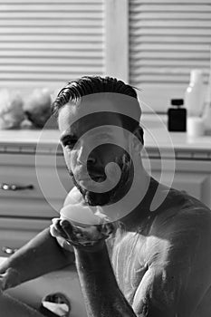 Sex and erotica concept. Man with beard and seductive face blowing foam from palm. Man with beard and seductive face photo