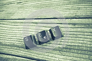SEX wrote with keyboard keys on wooden background, green vinta