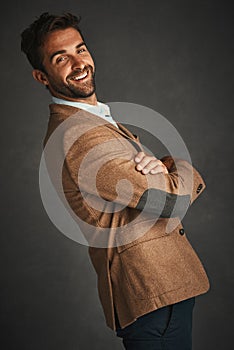 The sexiest man has a beard and smile. Studio shot of a handsome young man posing against a gray background.