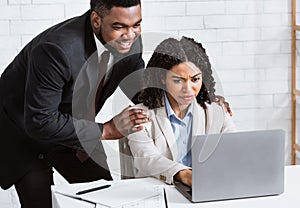 Sexual harassment at workplace. African American male boss touching his beautiful female secretary at company office