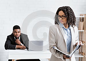 Sexual intimidation concept. Perverted black businessman looking at his female colleague from behind at office