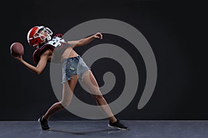 Sexual sportive woman running with rugby ball and screaming aggressively at black background. gender equality