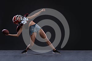 Sexual sportive woman running with rugby ball and screaming aggressively at black background. gender equality