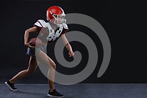 Sexual sportive woman running with rugby ball and screaming aggressively at black background. gender equality