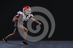 Sexual sportive woman running with rugby ball and screaming aggressively at black background. gender equality