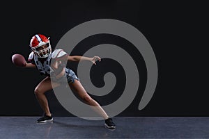 Sexual sportive woman running with rugby ball and screaming aggressively at black background. gender equality