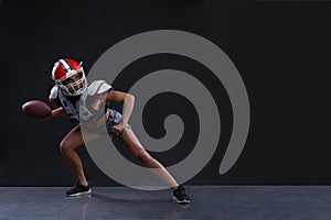 Sexual sportive woman running with rugby ball and screaming aggressively at black background. gender equality