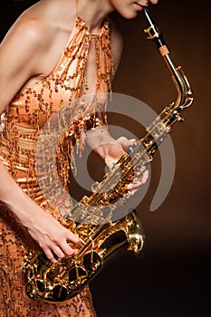 Sexual young woman posing with saxophone at studio