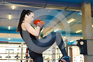 Sexy athletic girl makes a kick in the gym. woman in boxing gloves trains the knee.