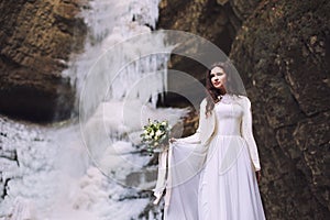 bride with a wedding bouquet of flowers on a background with a glacier and mountains
