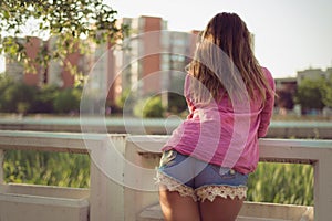 and attractive woman posing with her back, watching at something, wearing casual denim shorts