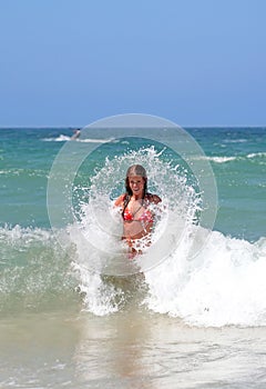 attractive young girl being splashed by cold wave in the se photo