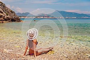 Sexy back of beautiful woman in bikini and creative hat on sea background. Sea coast near Kemer, Antalya, Turkey